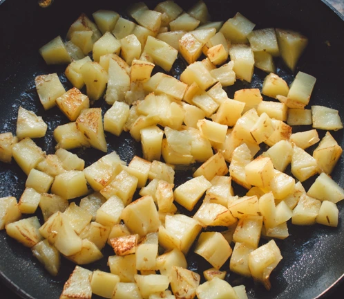 Diced potatoes browning in a skillet for a chicken and egg breakfast skillet recipe.