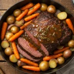 Sliced chuck roast with gravy, baby potatoes, carrots, and onions in a Dutch oven