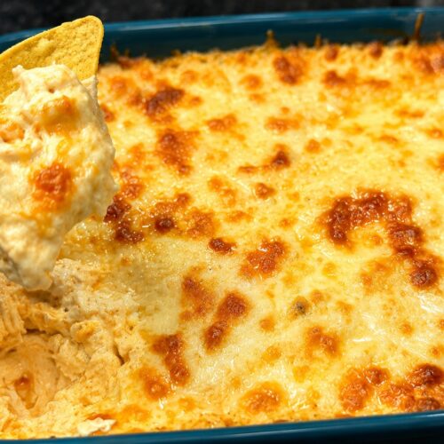 Creamy Buffalo chicken dip with melted cheese scooped with a tortilla chip