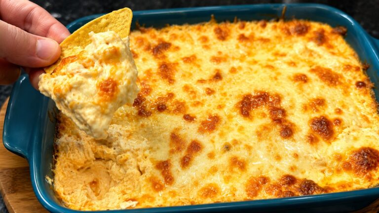 Creamy Buffalo chicken dip with melted cheese scooped with a tortilla chip